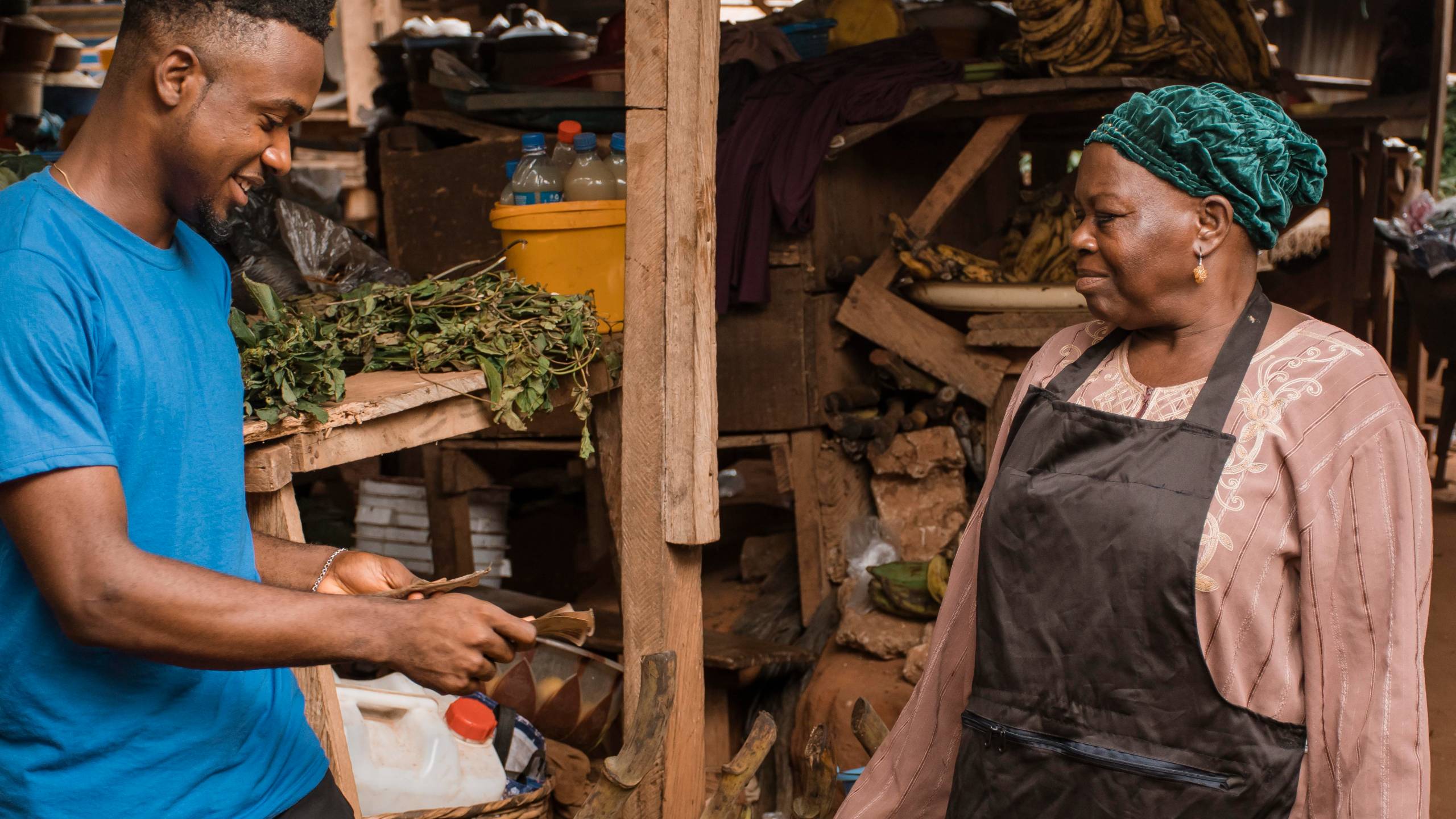 A customer paying a trader at her stall in a Ghanaian market